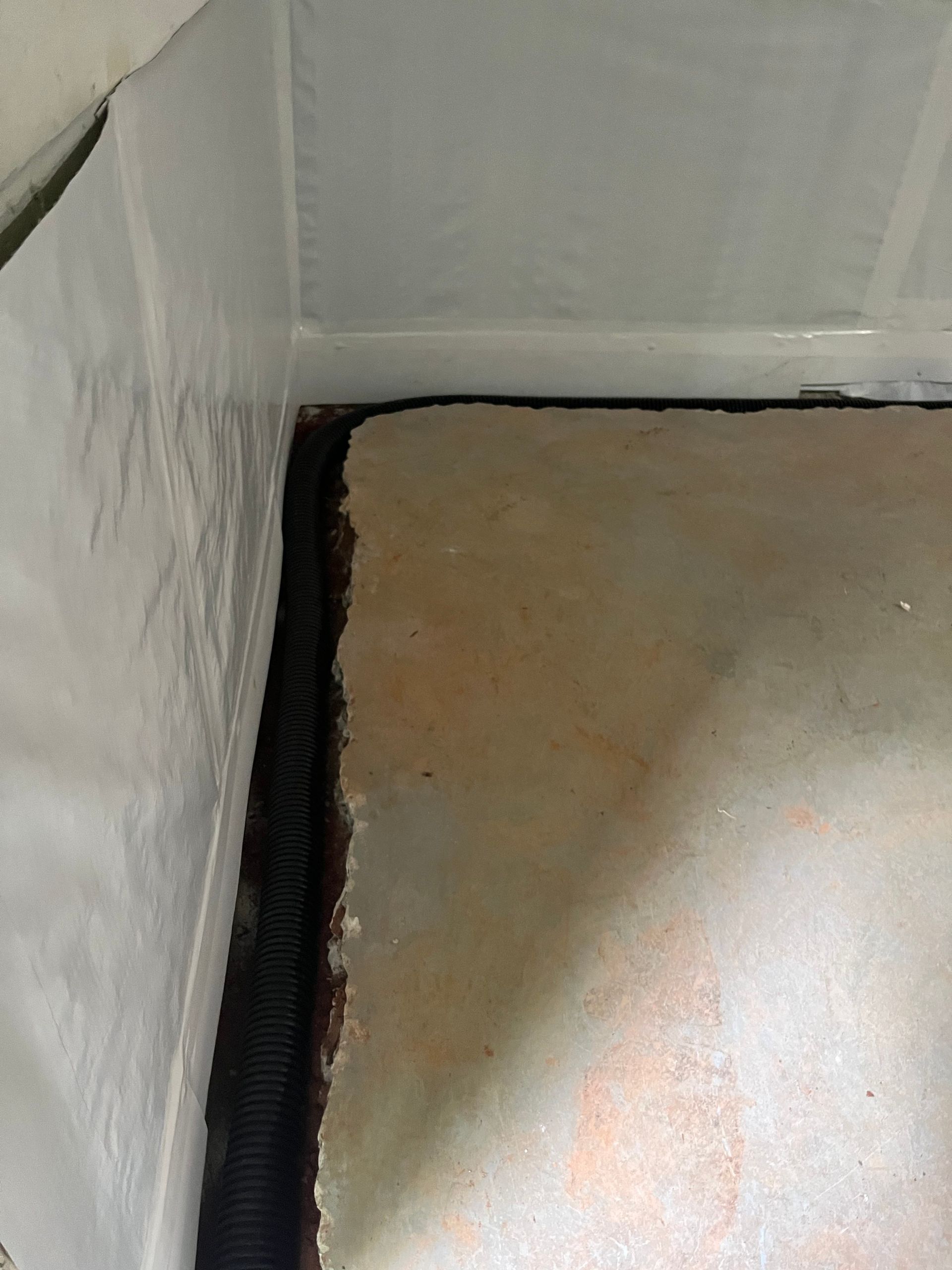 Close-up of a wall corner with a black seam and a beige floor surface.