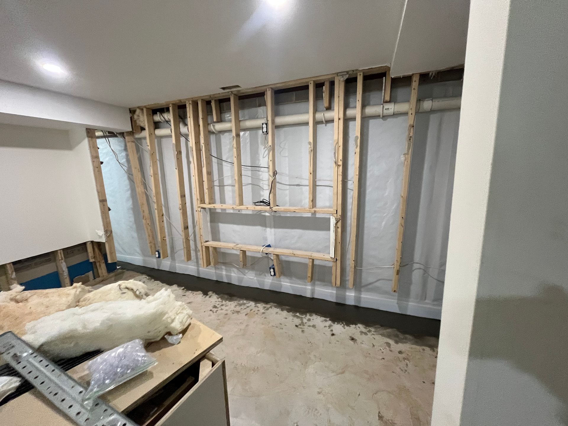 Interior room under renovation with exposed wall studs and construction materials on the floor
