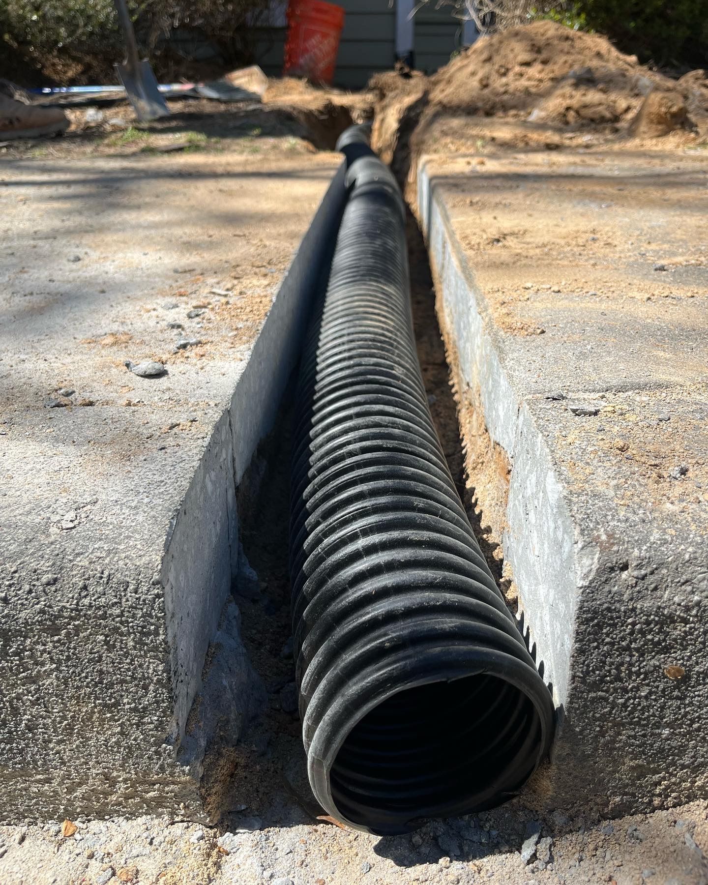 Black corrugated drainage pipe laid in a concrete trench at a construction site