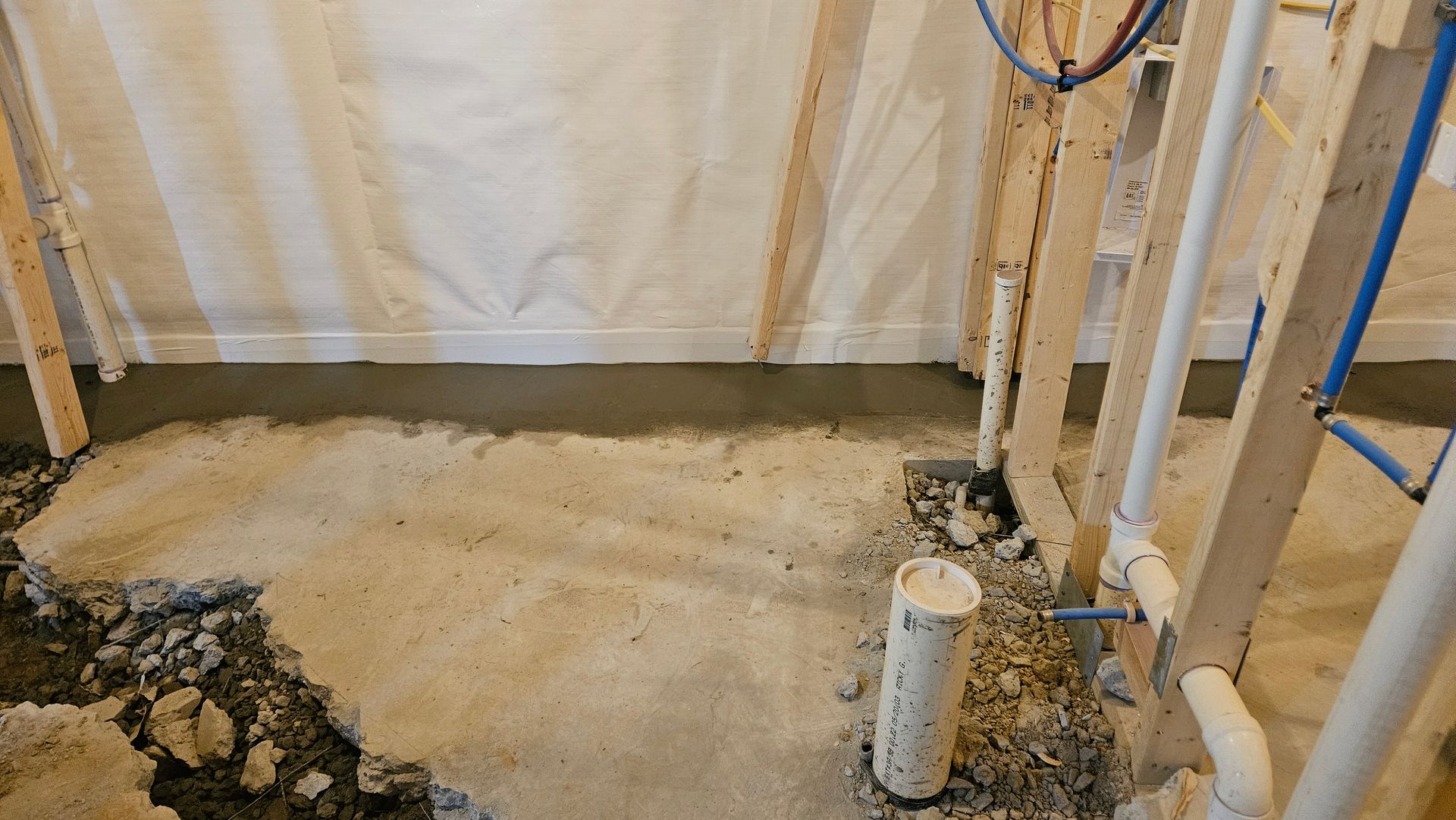 Basement utility area with unfinished concrete floor, exposed pipes, and insulated walls during construction