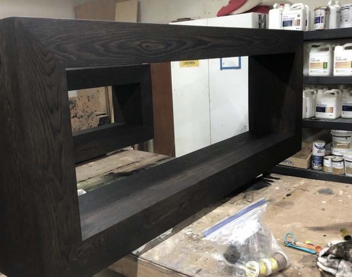 Dark stained wood frame with open rectangular spaces, resting on a workbench.
