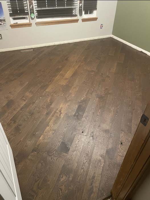 Dark wood flooring in a room with white trim and a green wall.