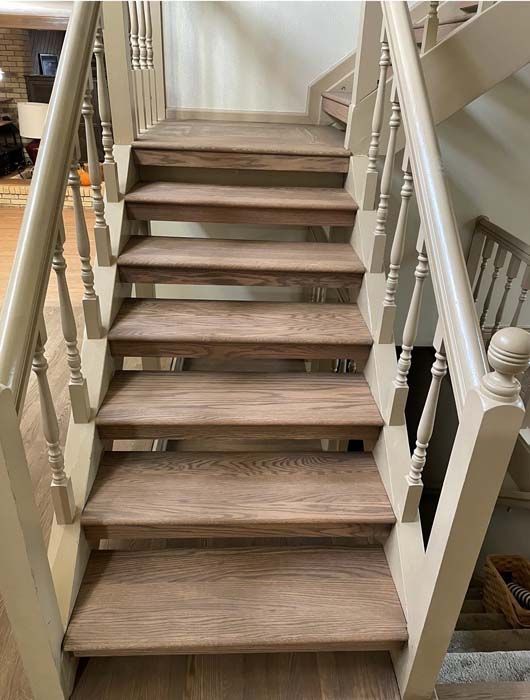 Wooden staircase with light beige banisters and dark wooden steps.