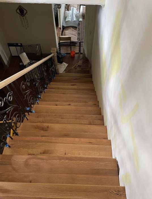 Wooden staircase with decorative iron railing descends to a hallway.