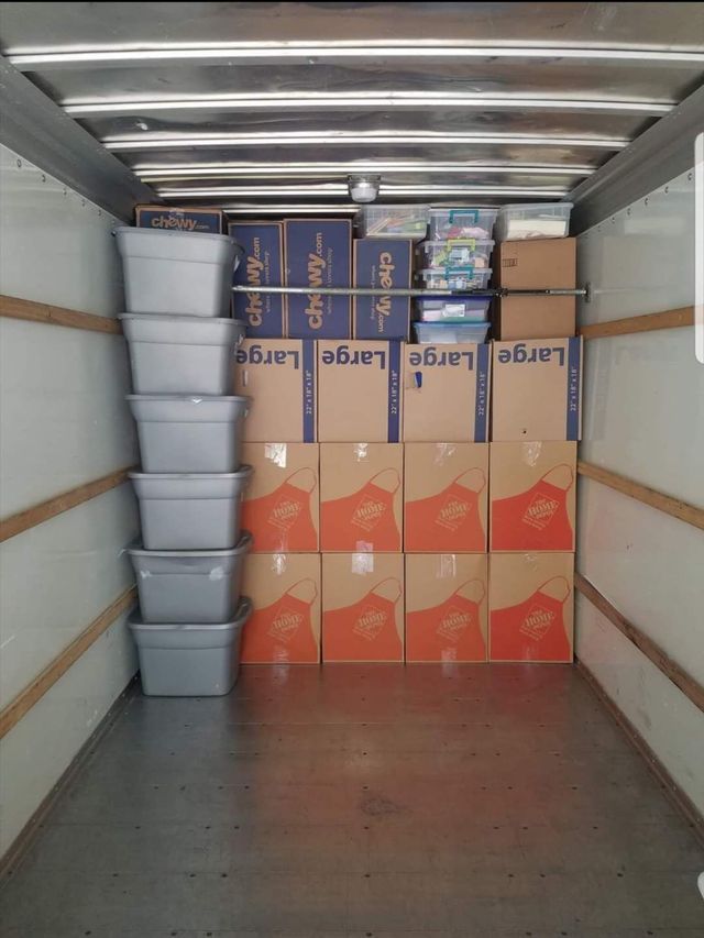 Cargo trailer filled with stacked boxes and plastic bins, organized for transport