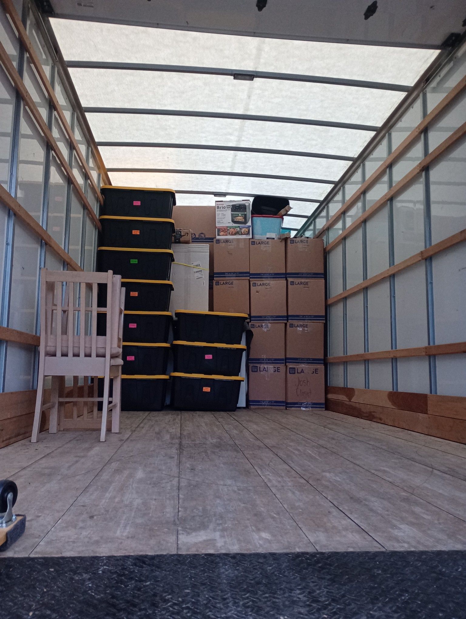 Empty moving truck with stacked boxes and plastic bins inside
