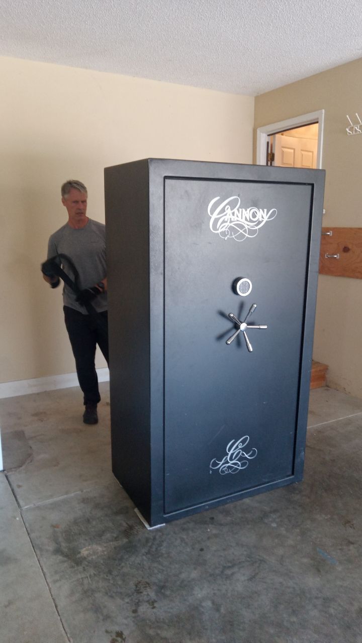 Man standing beside a large black gun safe in a garage