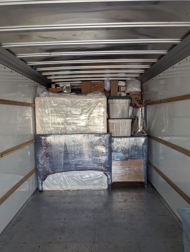Cargo trailer interior packed with wrapped boxes and furniture against the front wall