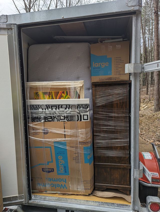 Packed moving truck with boxed household items, including a sofa and wrapped furniture.