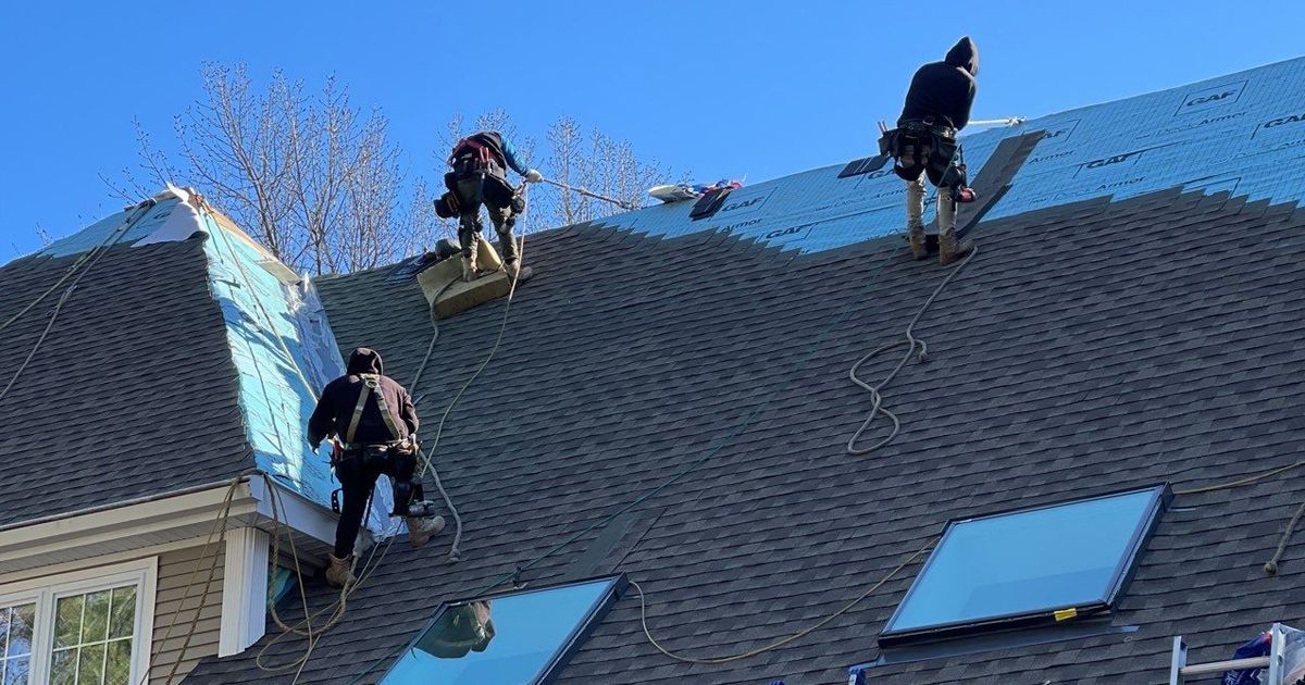 A group of men are working on the roof of a house.