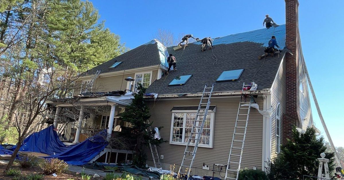 A group of people are working on the roof of a house.