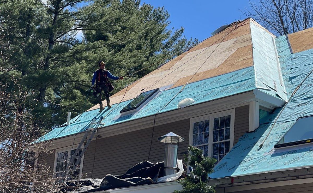 A man is standing on the roof of a house.