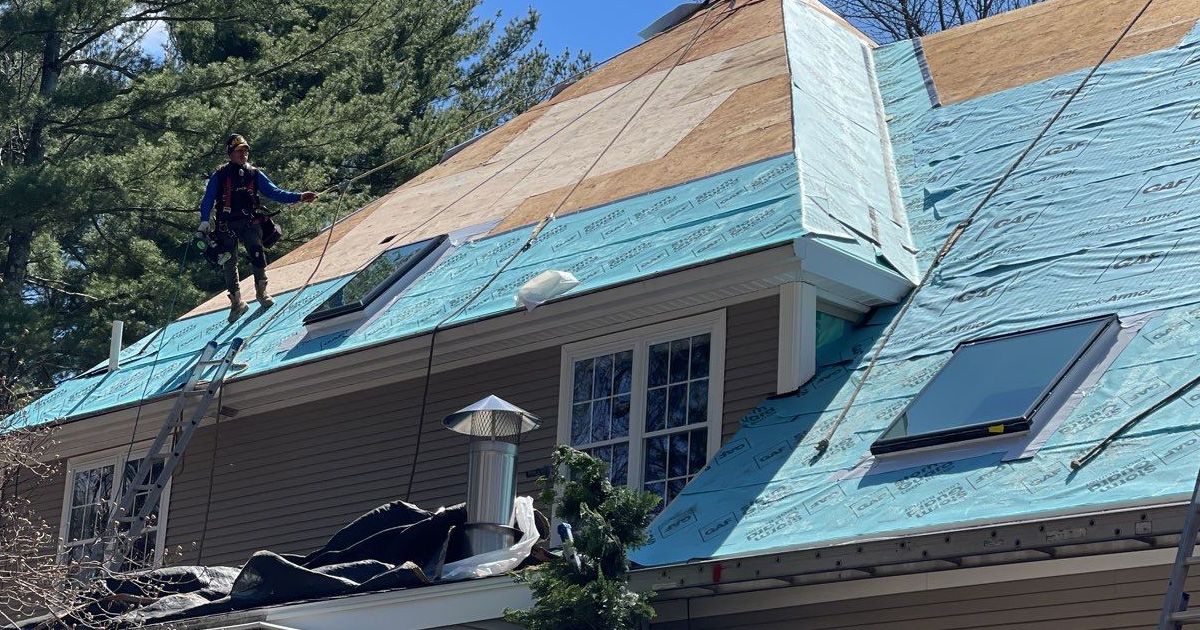 A man is standing on the roof of a house.