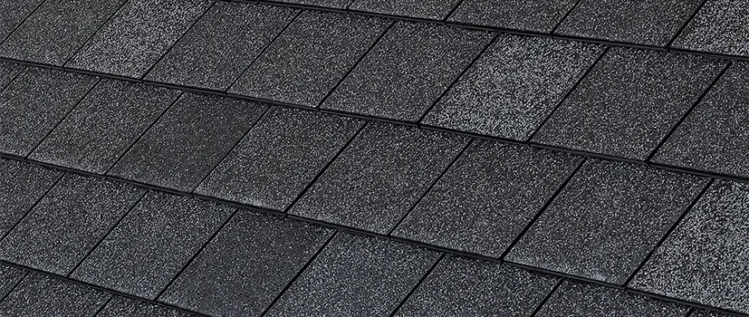 Close-up of black asphalt shingles on a roof, angled perspective.