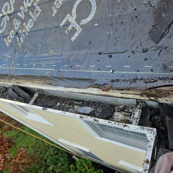 A dirty gutter filled with debris, with Ice & Water Shield visible above.