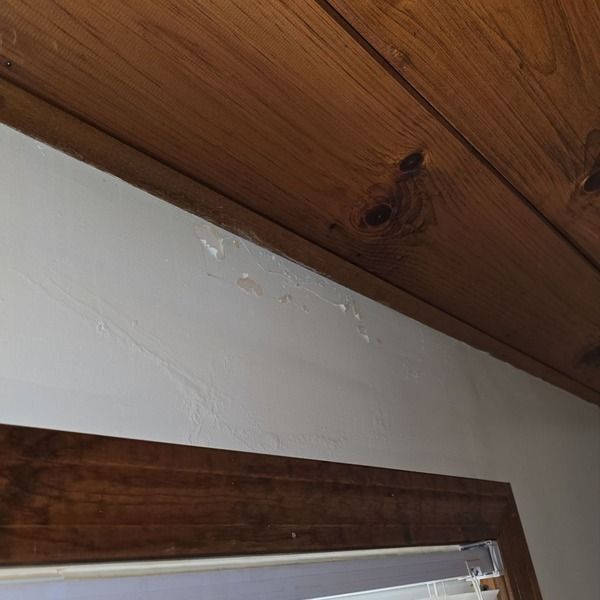 Ceiling water stain from active roof leak above window