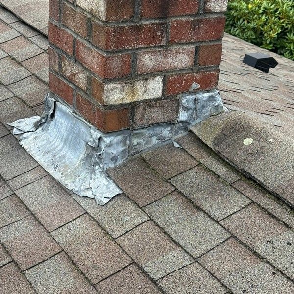 Deteriorated chimney flashing on an aging asphalt shingle roof