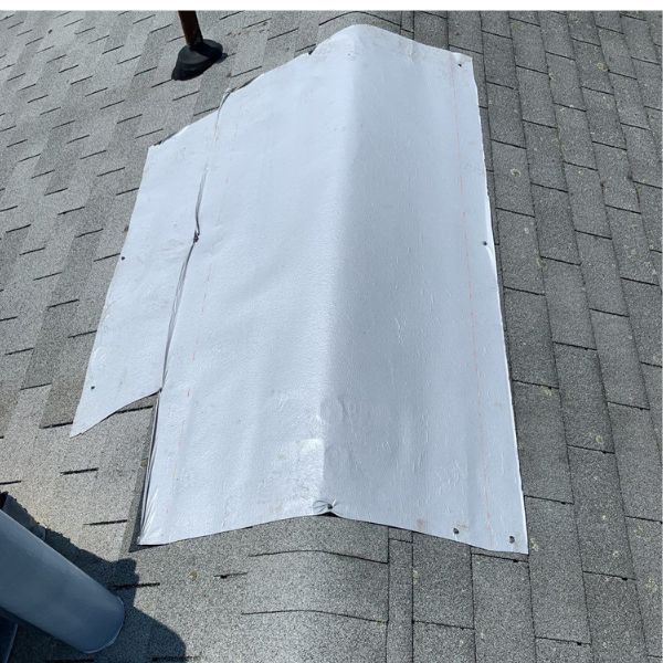 White flashing on a gray shingle roof, covering a corner. A black object is in the background.