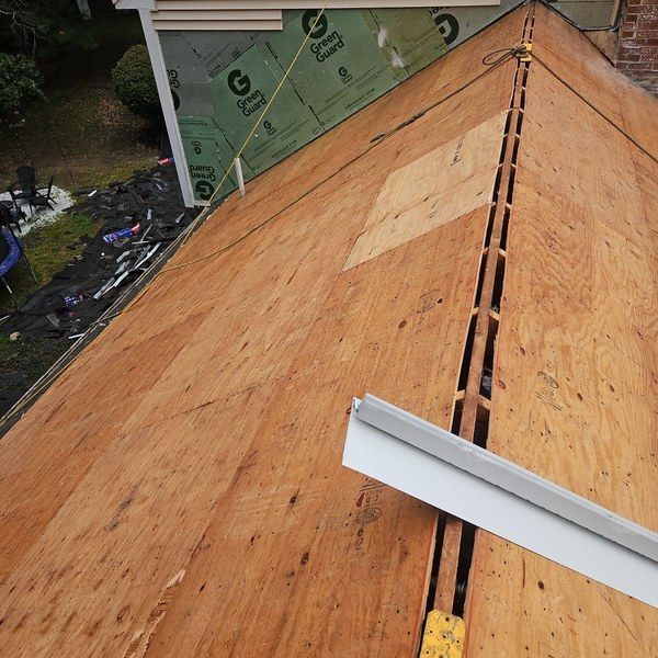 Roof decking exposed with the ridge cut open for a new continuous ridge vent in Blackstone MA