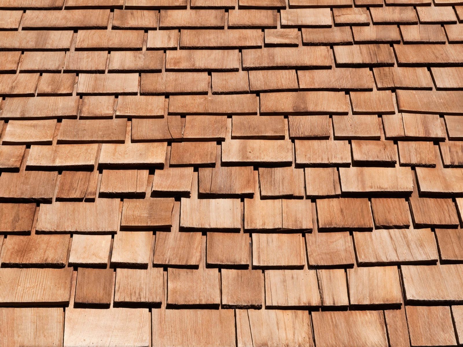 Close-up of a brown cedar shingle roof, showing overlapping rectangular tiles.