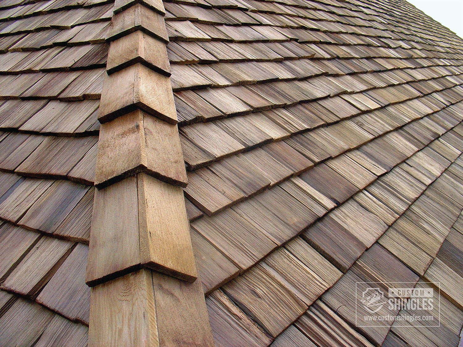 Cedar shake roof with pointed ridge detail, showing weathered wood texture.