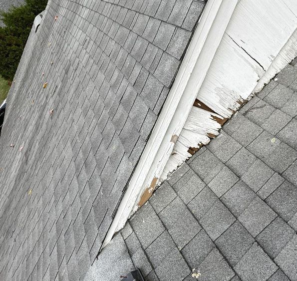 Gray asphalt shingle roof with worn, damaged trim.