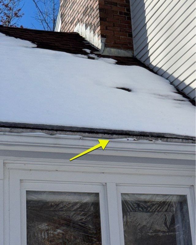 Snow-covered roof with a chimney and an arrow pointing to the edge of the roof above a window.