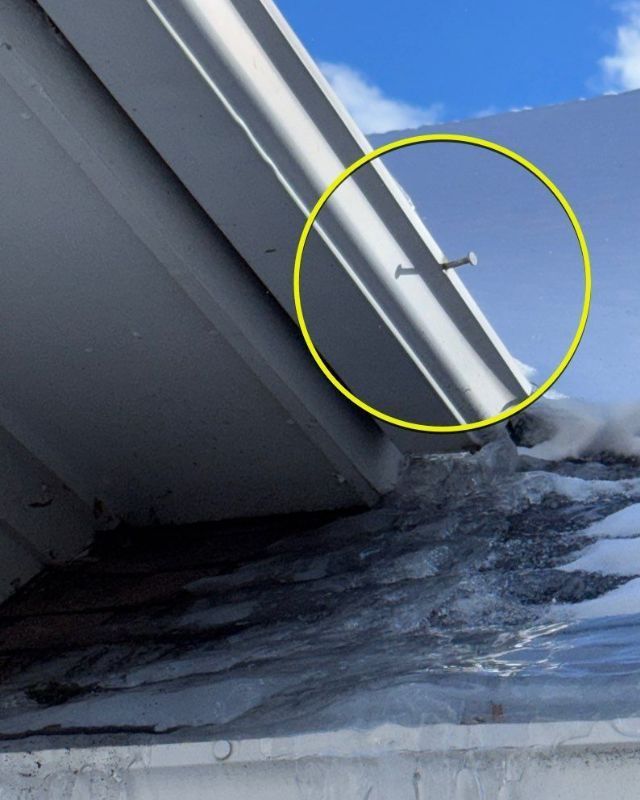 Close-up of a metal roof with a partially hammered nail.