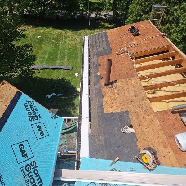 Roof being replaced, plywood exposed, with GAF StormGuard underlayment and tools.