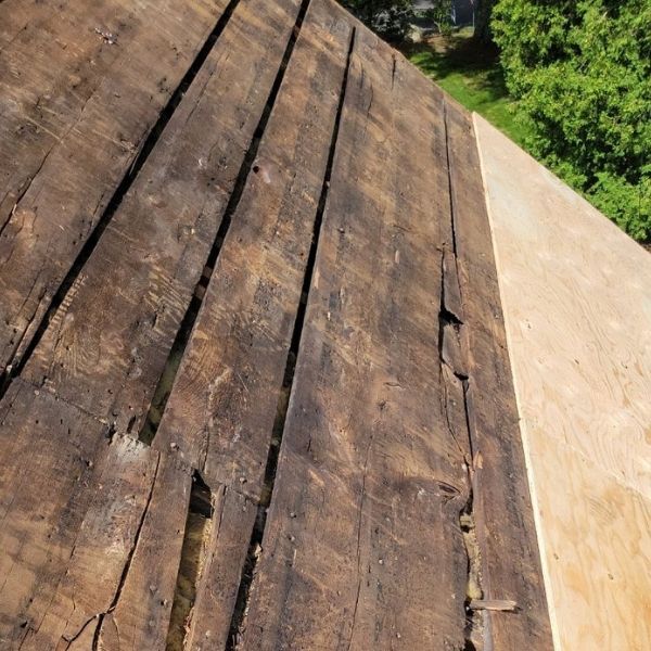 Close-up of weathered wooden boards on a roof. Light wood is next to dark wood with deep cracks.