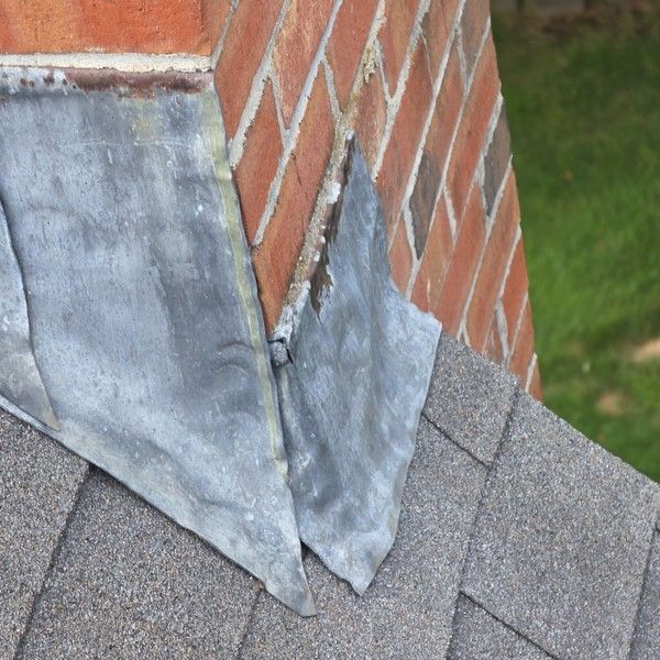 Weathered metal chimney flashing on an aging asphalt shingle roof