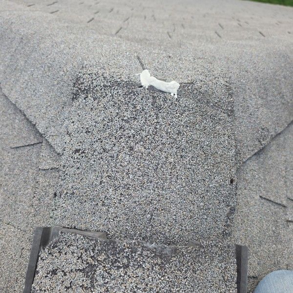 Cracked asphalt ridge cap shingle patched with sealant