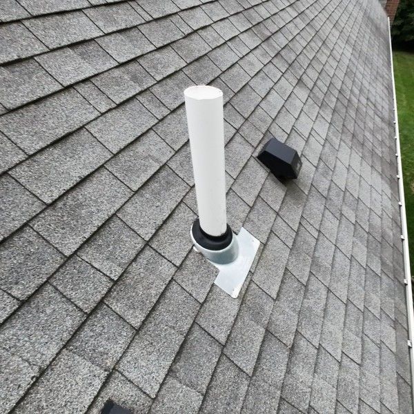 Plumbing vent pipe boot and bathroom exhaust vent on a worn 3-tab shingle roof before replacement