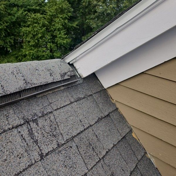 Worn ridge vent, weathered shingles and exposed roof-to-wall joint at a gable on an aging Holliston MA roof
