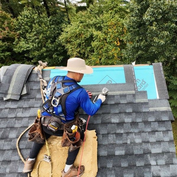 Roofer wearing a safety harness installing GAF Timberline UHDZ shingles over GAF StormGuard leak barrier in Holliston MA