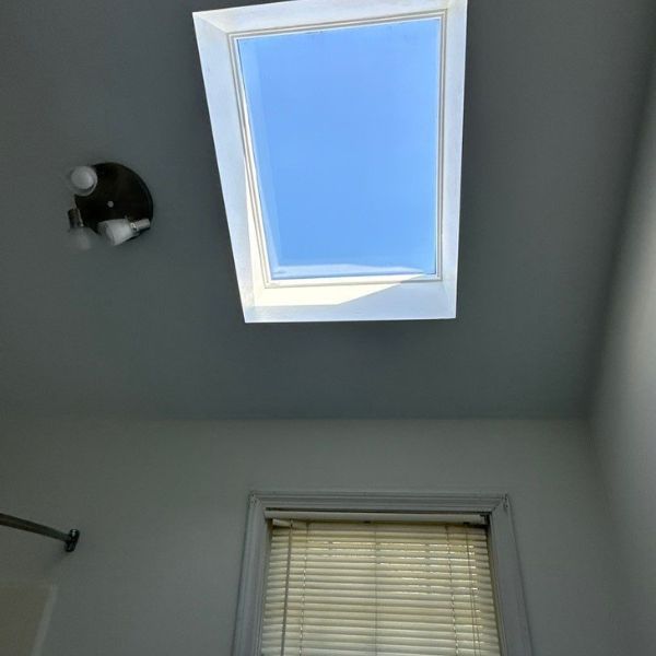Bathroom with skylight and small window; blue sky visible through the skylight.