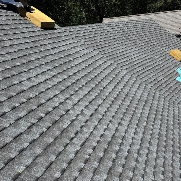 Dark gray shingle roof, with wooden beams at the top. The shingles have a textured appearance.