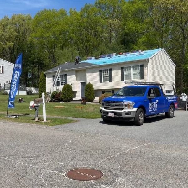 Home with roof under repair and Master Roof truck in the driveway.
