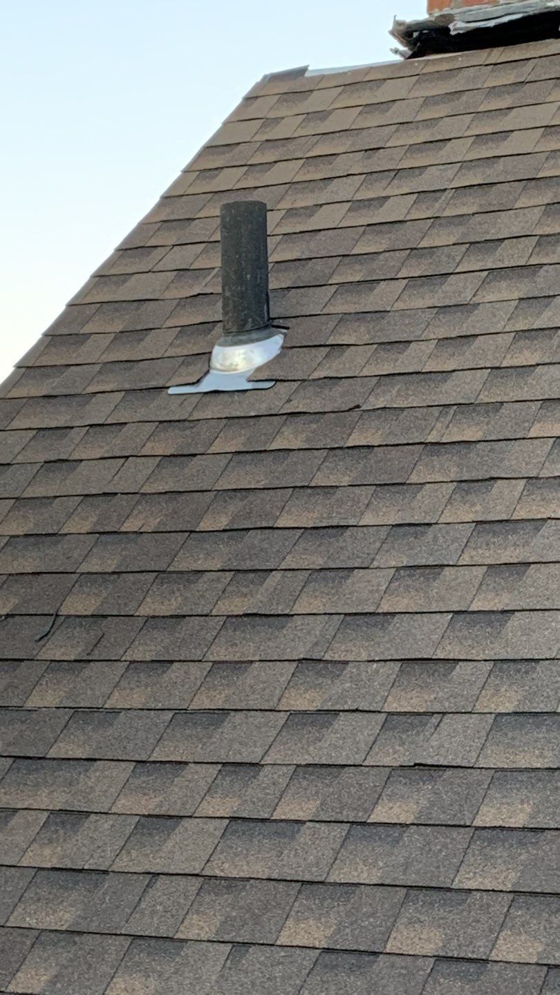 Gray asphalt shingle roof with a vent pipe and flashing.