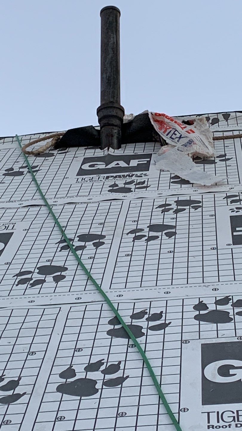 Roof with vent pipe. Black pipe protruding from roof. Underlayment with paw prints.