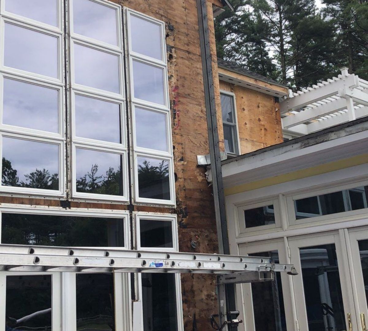 Building exterior with large windows under construction; ladder in front.