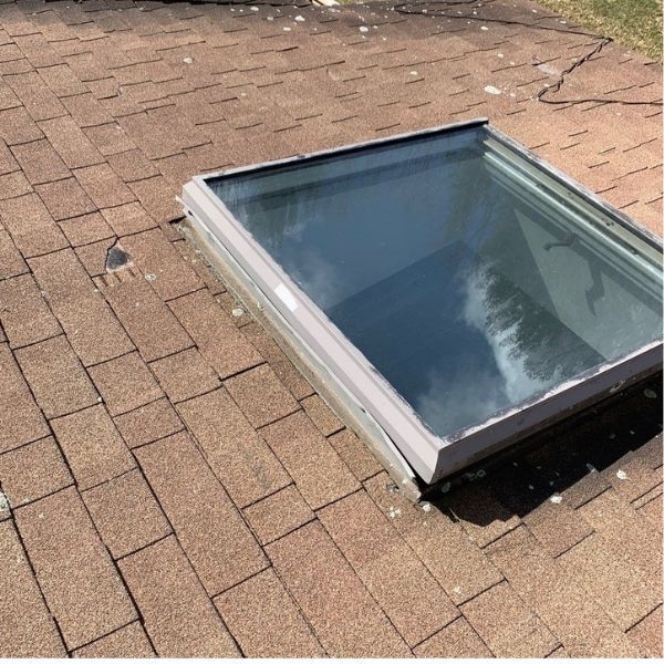 A rectangular skylight installed on a brown asphalt shingle roof.