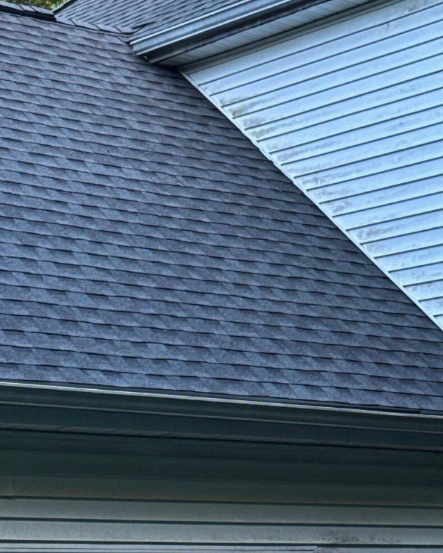 Dark gray shingle roof next to light blue siding. A gutter is visible along the roof's edge.