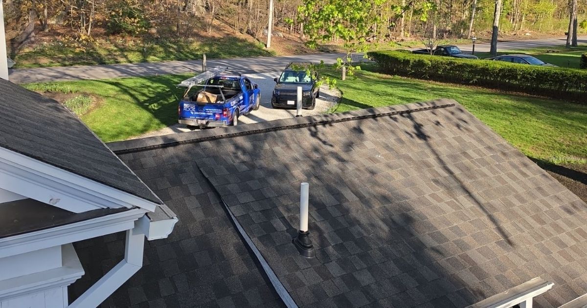 View over a new roof into the driveway with a truck and a SUV