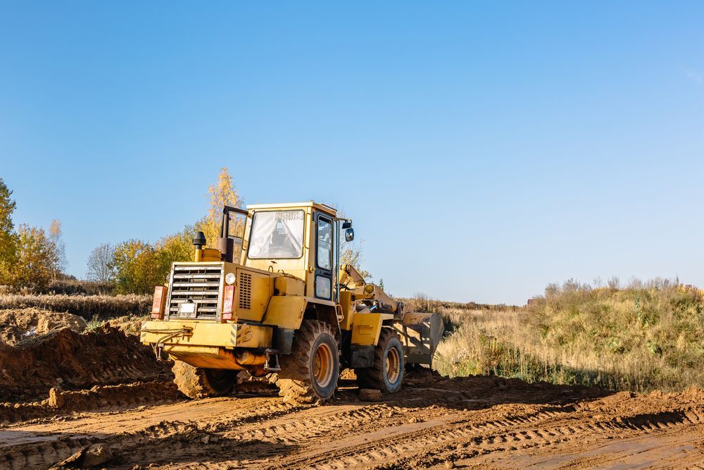 Yellow bulldozer on a dirt road at a construction site under a clear blue sky