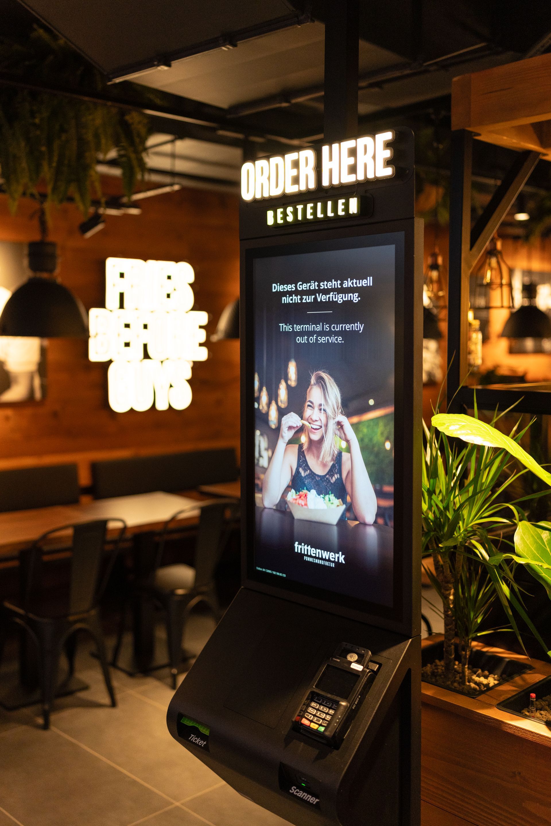 Innenausbau Frittenwerk Flensburg - Restaurantumbau - Restaurant Innenraum mit maßgeschneiderten Schreinermöbeln und Sitzgelegenheiten im Industriestil und digitalem Bestellschalter - Referenzprojekt Generalunternehmer Innenausbau