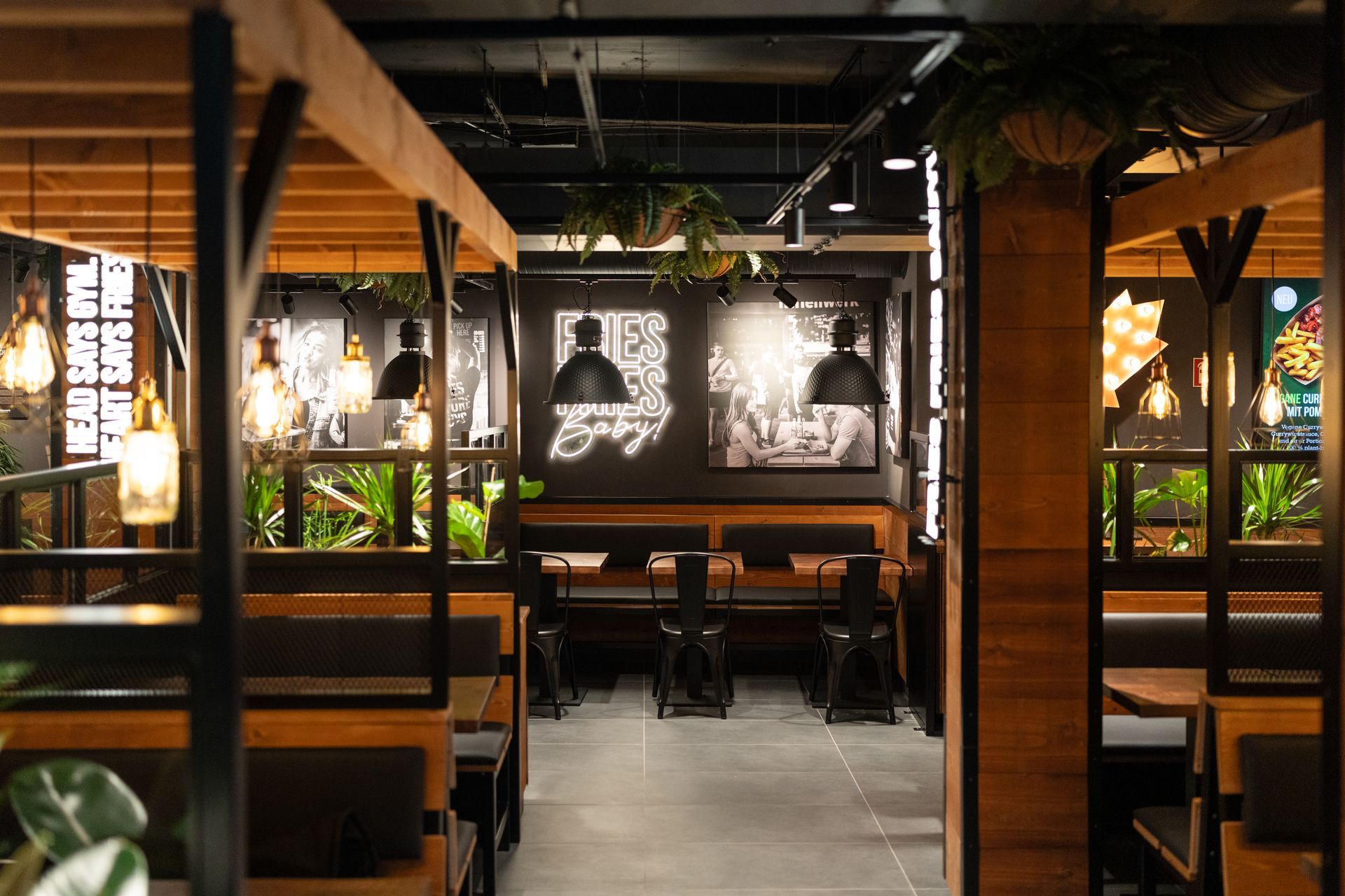 Innenausbau Frittenwerk Flensburg - Restaurantumbau - Stilvoller Gastronomie-Innenausbau mit Holzelementen, modernen Sitzbereichen, Wandbildern und stimmungsvoller Beleuchtung - Referenzprojekt Generalunternehmer Innenausbau