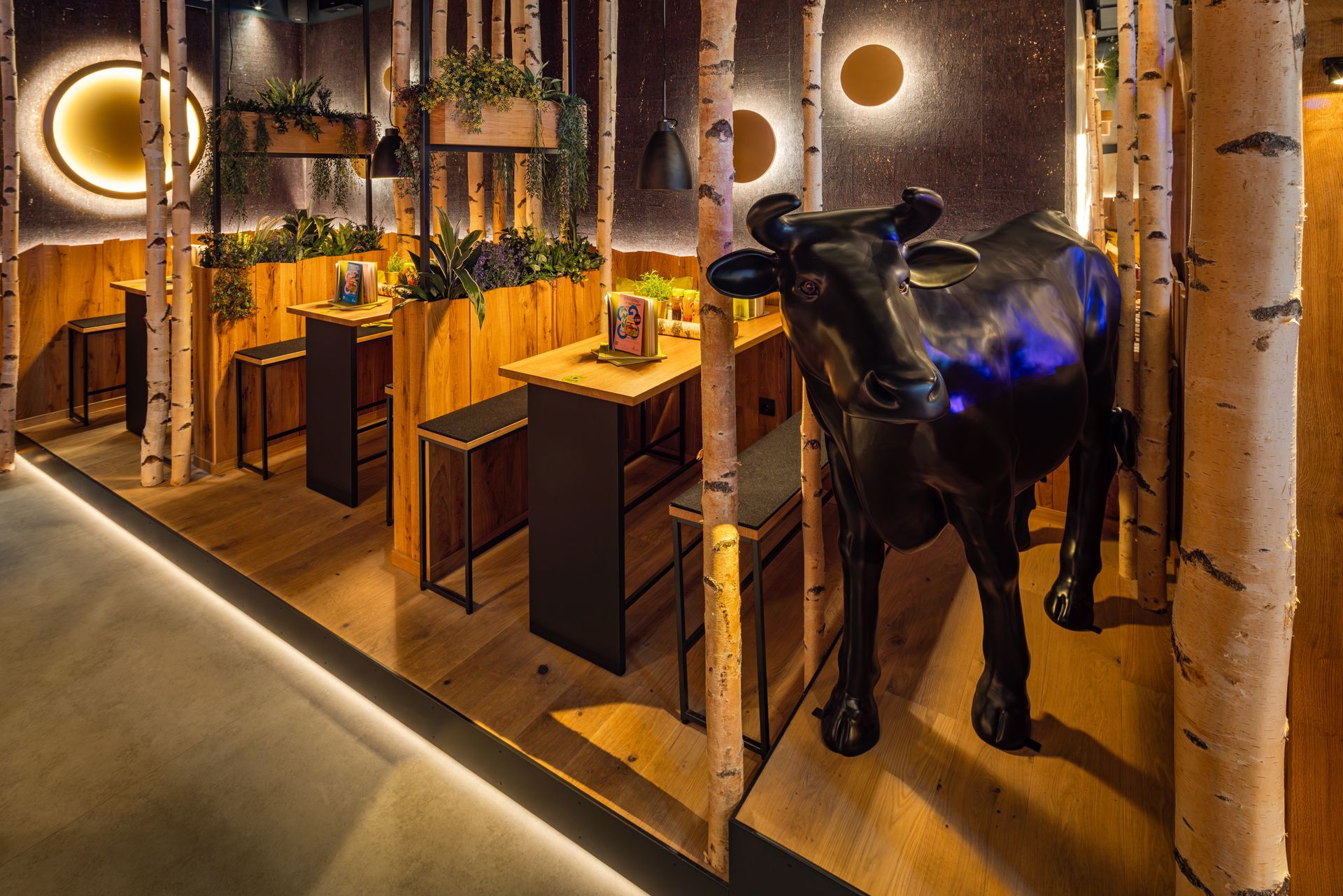 Hans im Glück Berlin - Moderner Gastronomie-Innenbereich mit Sitzbänken, Holzelementen und dekorativer Kuh – Referenzprojekt Restaurantumbau Generalunternehmer Innenausbau