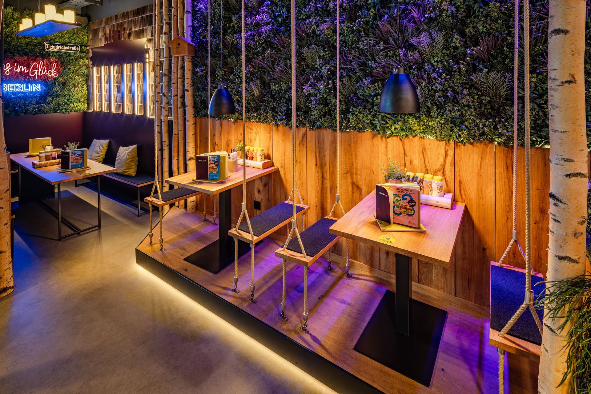 Innenausbau-Projekt Restaurantrenovierung Hans im Glück Berlin - Innenraum mit Birkenstämmen, Pflanzen & warmer Beleuchtung - Referenzprojekt für schlüsselfertigen Innenausbau Generalunternehmung
