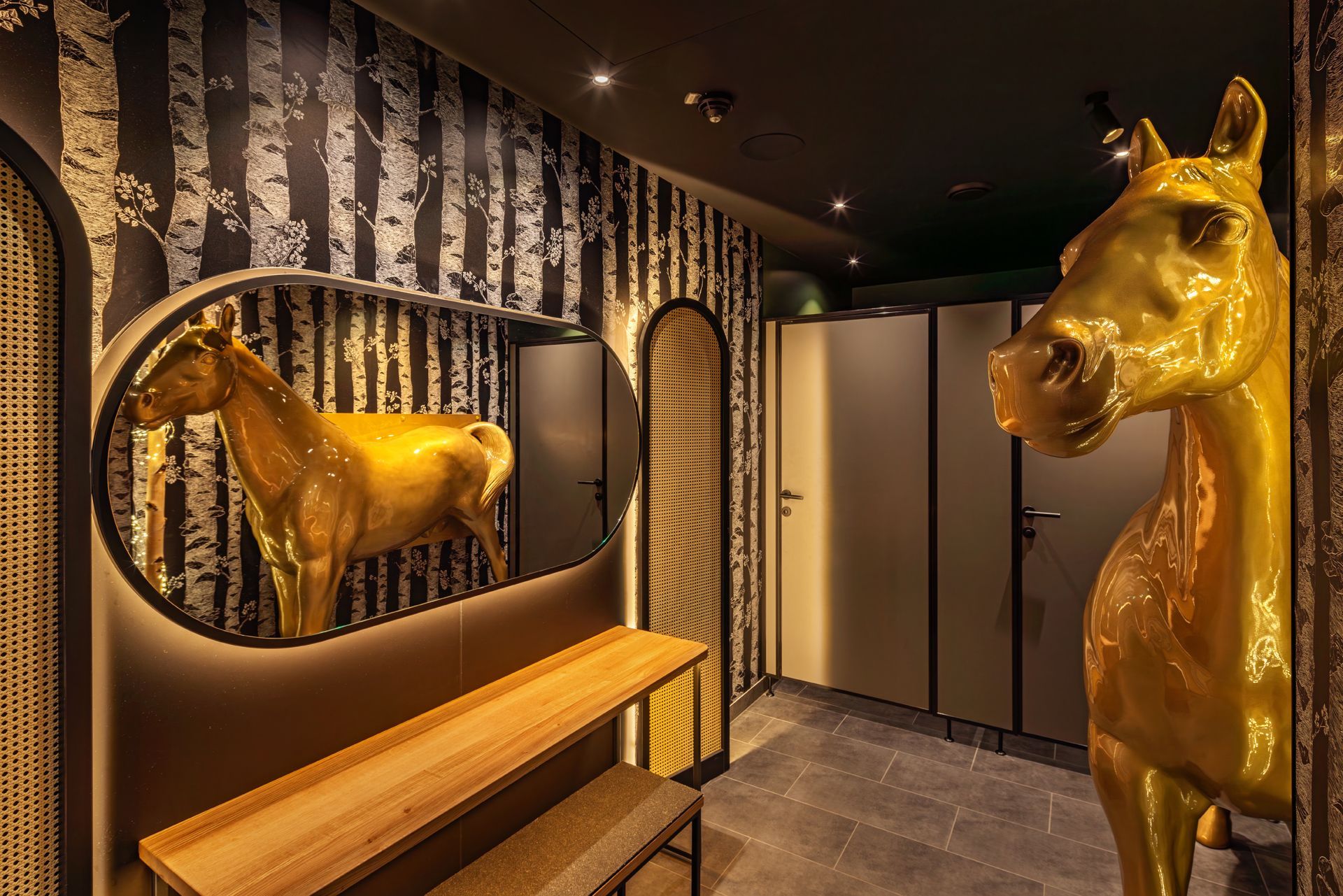 Hans im Glück Wien - Restaurant Badezimmer, Toilettenbereich mit dekorativen Wandelementen, goldenes Pferd mit Spiegel und stilvoller Inneneinrichtung – Referenzprojekt Restaurantumbau Generalunternehmer Innenausbau